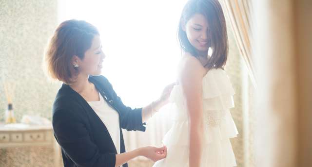 ドレス姿の花嫁とスタッフがサイズを確認している